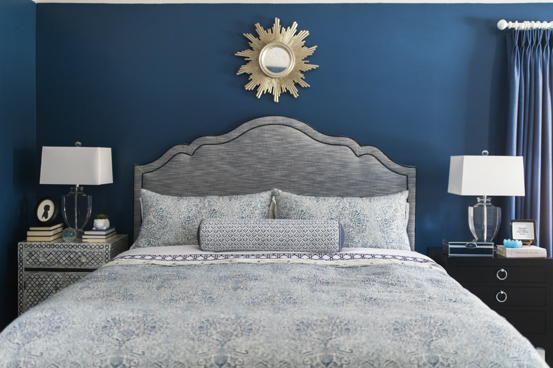 bed-sun-mirror-above-gray-fabric-headboard