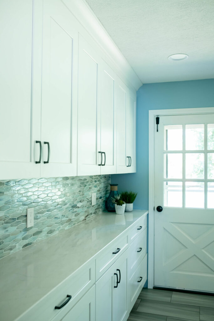 Gray and multicolored glass tile backsplash between white upper and lower cabinets. Kitchen Design Lindsey Putzier Design Studio