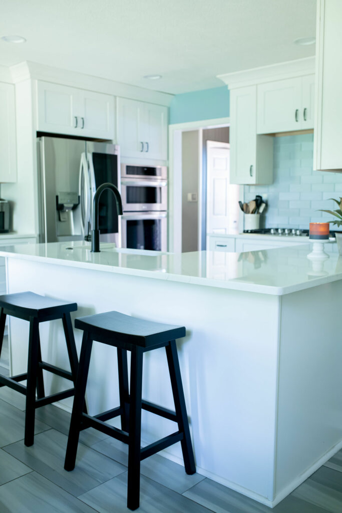 Black bar stools, white island, stainless kitchen appliances. Northfield, OH. Lindsey Putzier Design Studio