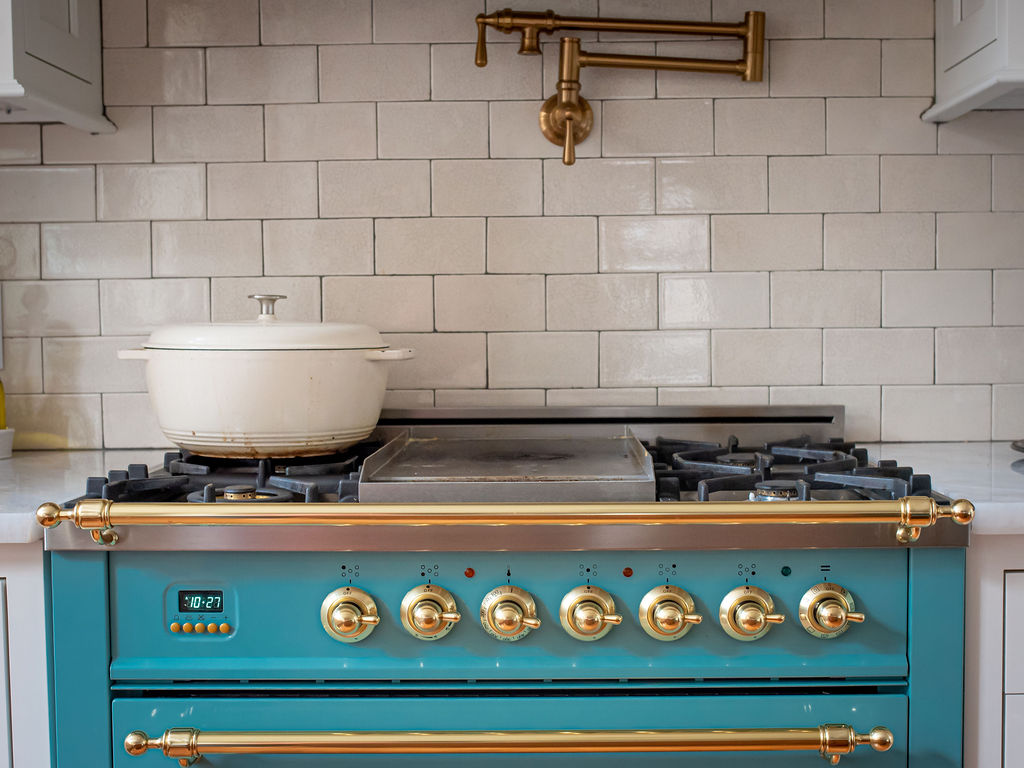 Teal European stove range beside white cabinetry with golden hardware Lindsey Putzier Design Studio