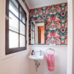 Powder room with white subway tile, colorful wallpaper, and dark wooden trim. Shaker Heights Ohio interior design Lindsey Putzier