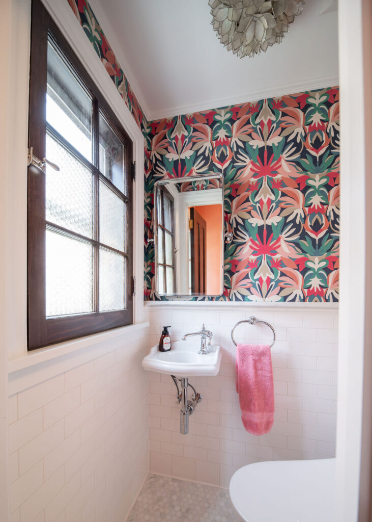 Powder room with white subway tile, colorful wallpaper, and dark wooden trim. Shaker Heights Ohio interior design Lindsey Putzier