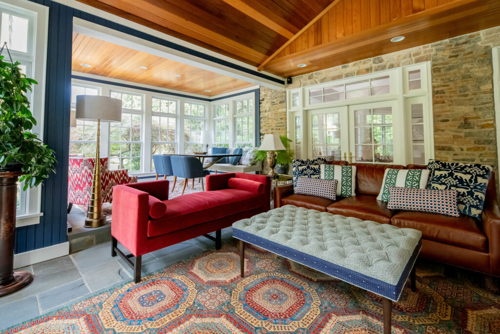 Red chaise, leather sofa, and Persian rug in wooded ceiling Sunroom Design Lindsey Putzier