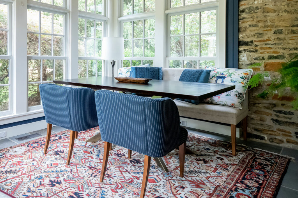 Authentic vintage rug, ;blue upholstered chairs, and large windows in Sunroom Lindsey Putzier