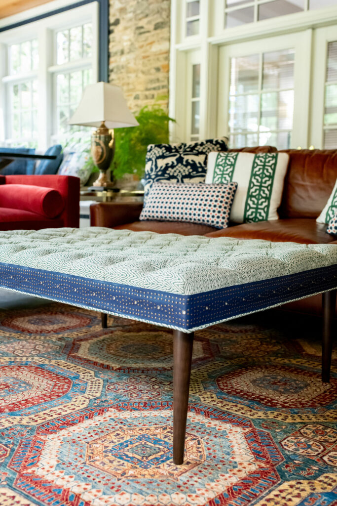 Small scale green print upholstered ottoman with navy leather trim on top of Persian Rug Lindsey Putzier