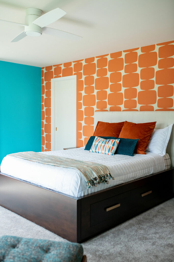 Patterned orange and white wallpapered accent wall with custom bed Lindsey Putzier Design Studio Ohio
