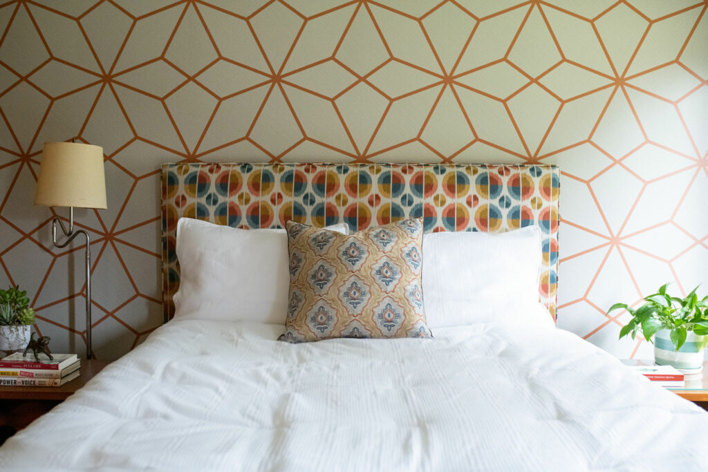 Geometric white with orange patterned wallpaper. Custom headboard and updated carpet in Bedroom design Lindsey Putzier Design Studio Hudson, OH