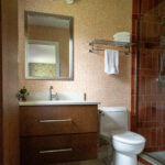 Orange patterned wallpaper and glass shower door in Bathroom design Lindsey Putzier Design Studio Ohio