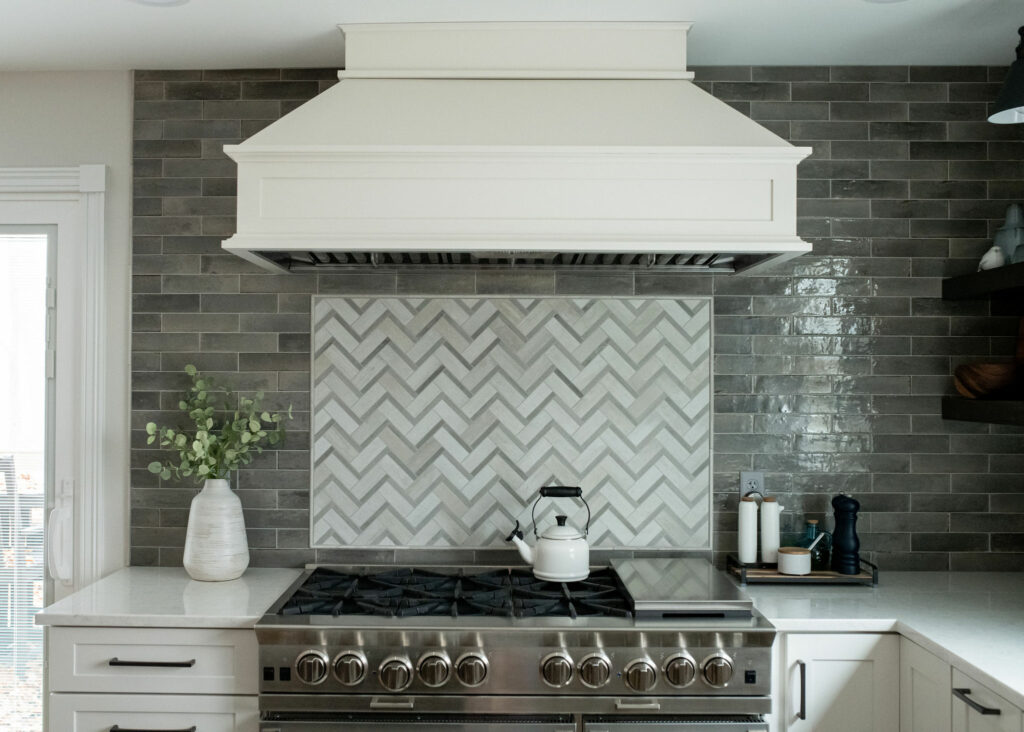 Herringbone accent tile above stove range with gray subway tile wall. Lindsey Putzier Design Studio