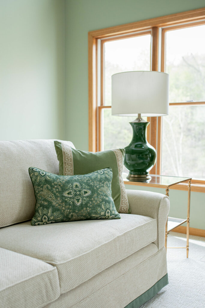Custom pillows for the sofa in different green patterns. Green table lamp on side table. Living Room Lindsey Putzier Design Studio Hudson, OH