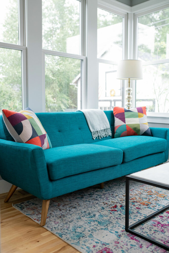 Teal sofa and multi-colored pillows in Sunroom design. Lindsey Putzier Design Studio. Hudson, OH