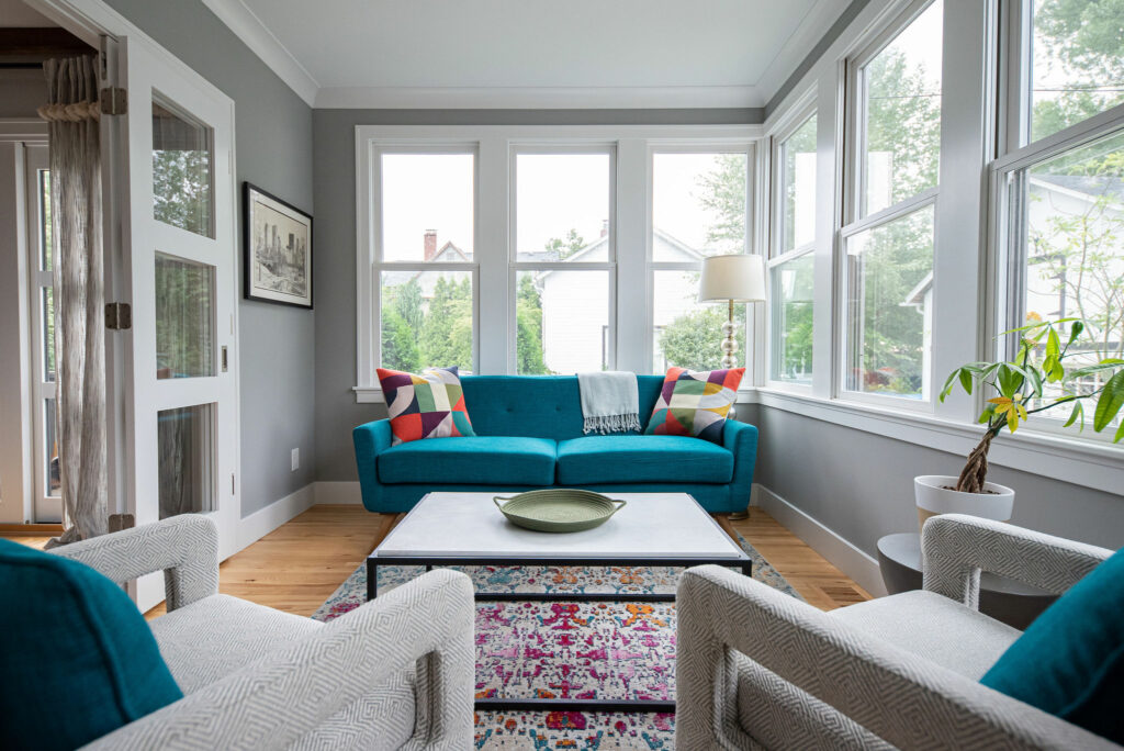 After image of Sunroom design with teal sofa and multi-colored pillows. Lindsey Putzier Design Studio. Hudson, OH