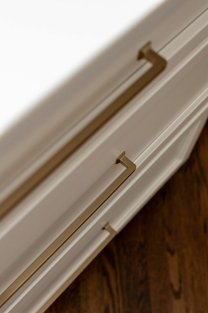 White cabinetry in Kitchen design with honey bronze hardware. Lindsey Putzier Design Studio Hudson, OH