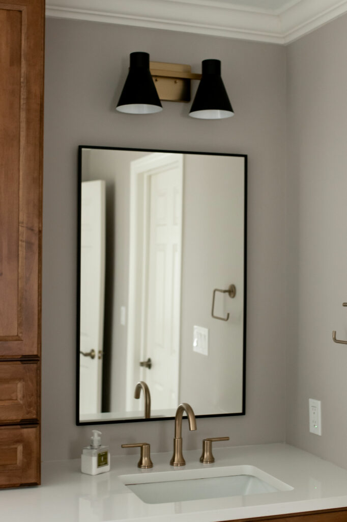 Black framed vanity mirror with black 2-light vanity light in maple cabinet double vanity area of Primary Bathroom. Lindsey Putzier Design Studio Hudson, OH