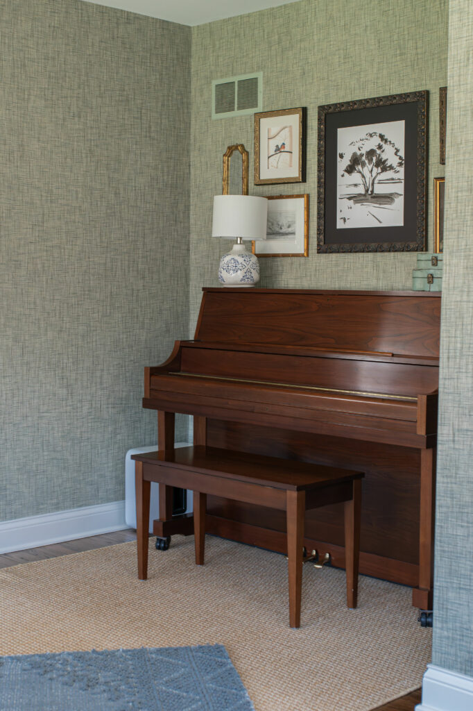 View of the piano with vintage art work arranged above it. Lindsey Putzier Design Studio, Hudson, Ohio