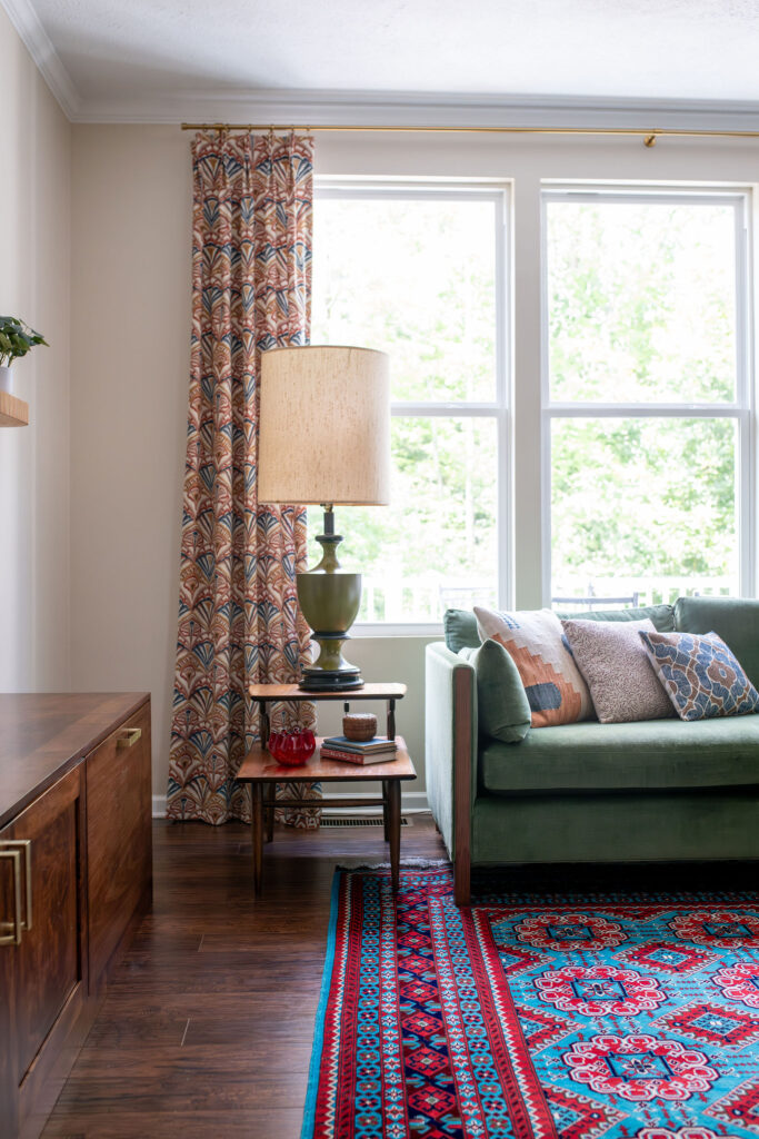 Custom drapes on large open window in the living room with a side table and vintage lamp. Hudson Ohio interior design Lindsey Putzier 