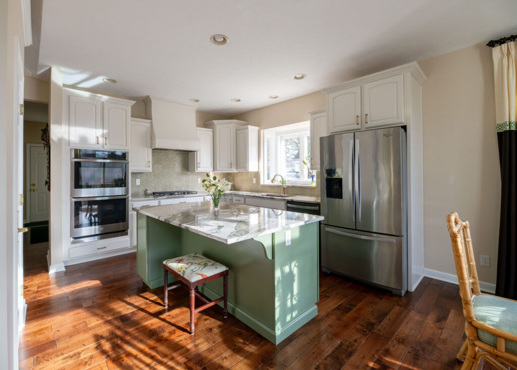 After of the kitchen remodel with earthy green island, painted white cabinets, and updated hood. Aurora Ohio interior design Lindsey Putzier
