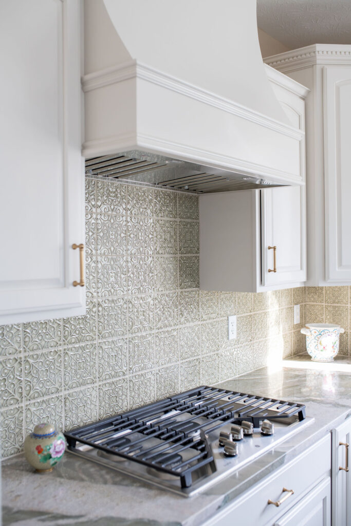 Updated vent hood in overtop the stove in the kitchen in Aurora Ohio with updated green backsplash tiles with texture. Lindsey Putzier interior design