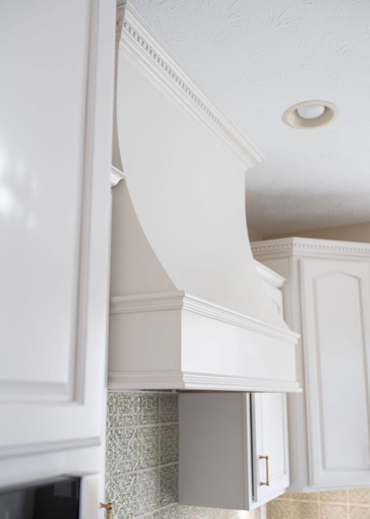 Updated vent hood in overtop the stove in the kitchen in Aurora Ohio with updated green backsplash tiles with texture. Lindsey Putzier interior design