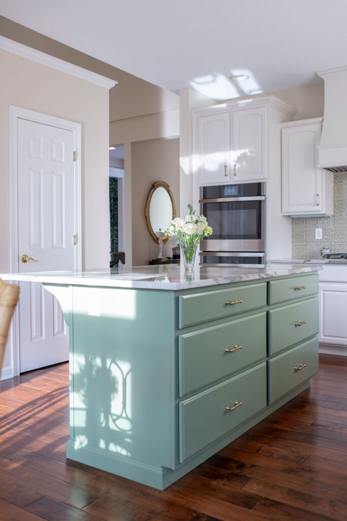 Earthy green island in the Aurora Ohio Kitchen remodel with green marble countertops and medium wooden flooring interior design Lindsey Putzier