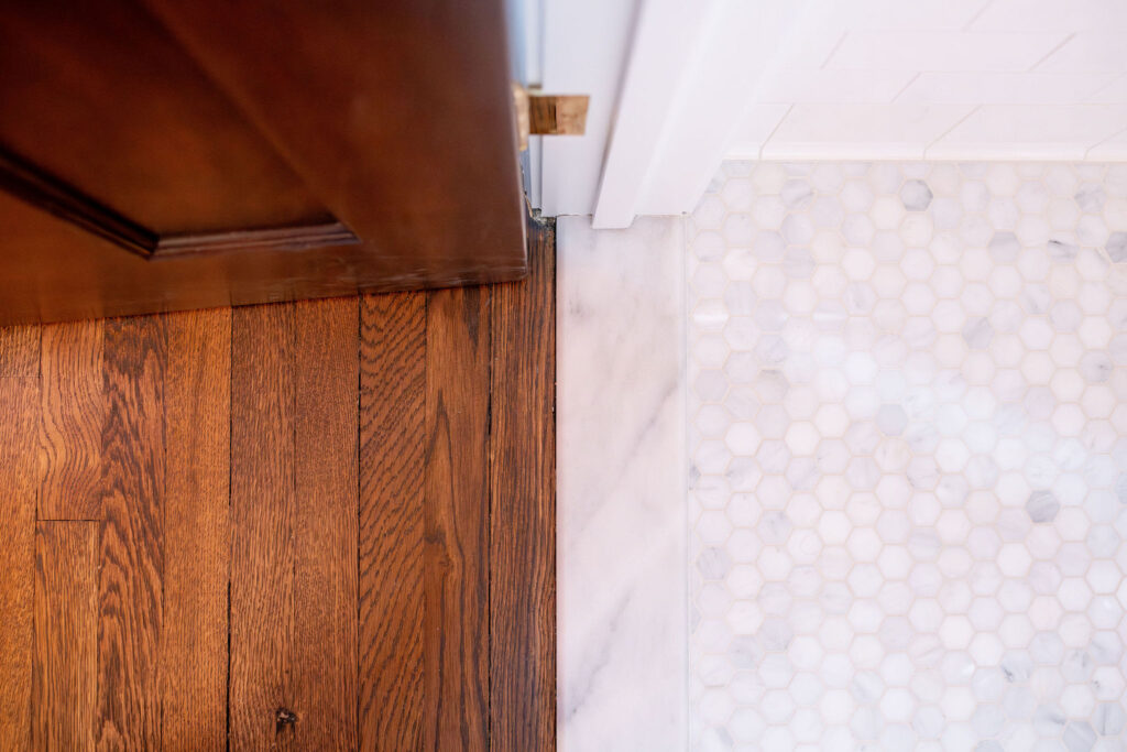 New flooring in the powder room with white tile flooring and hardwood flooring. Shaker Heights Ohio interior design Lindsey Putzier