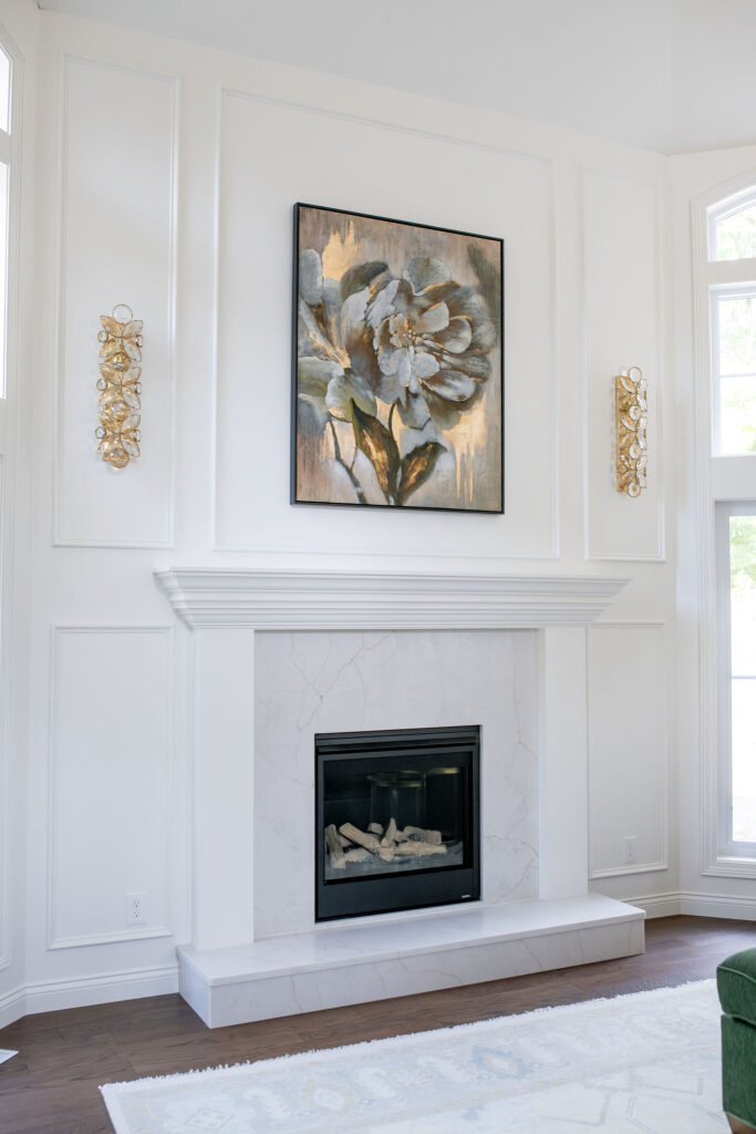 Fireplace in the living room with white tile and mantel. Gold painting and sconces to accent. Lindsey Putzier interior design Chagrin Falls Ohio