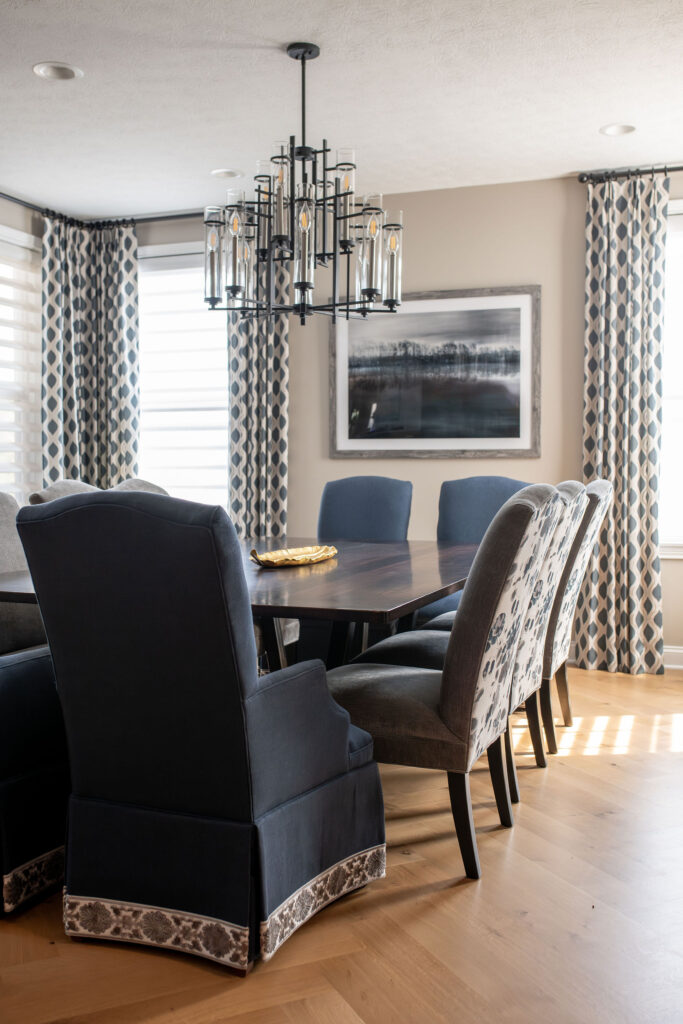 Candle chandelier hanging over the dining room table with herringbone hardwood flooring and blue color palette. Brecksville Ohio interior design Lindsey Putzier