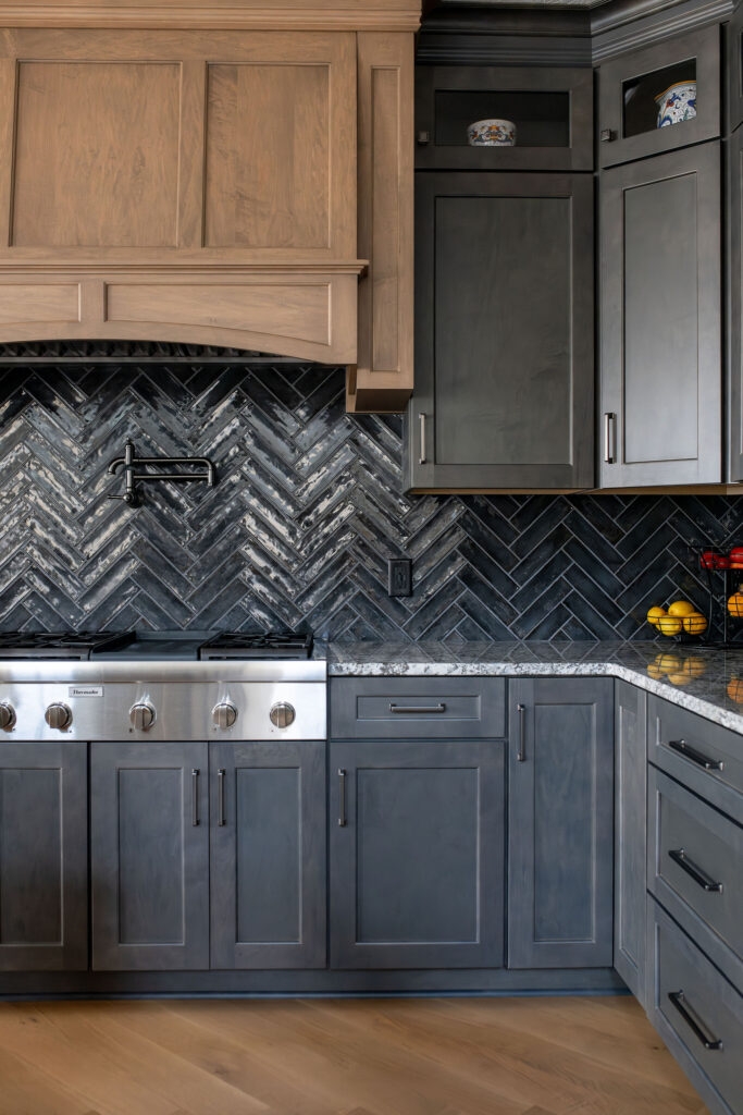 Black sleek herringbone tile backsplash and wooden range hood in the kitchen. Brecksville Ohio Interior Design Lindsey Putzier