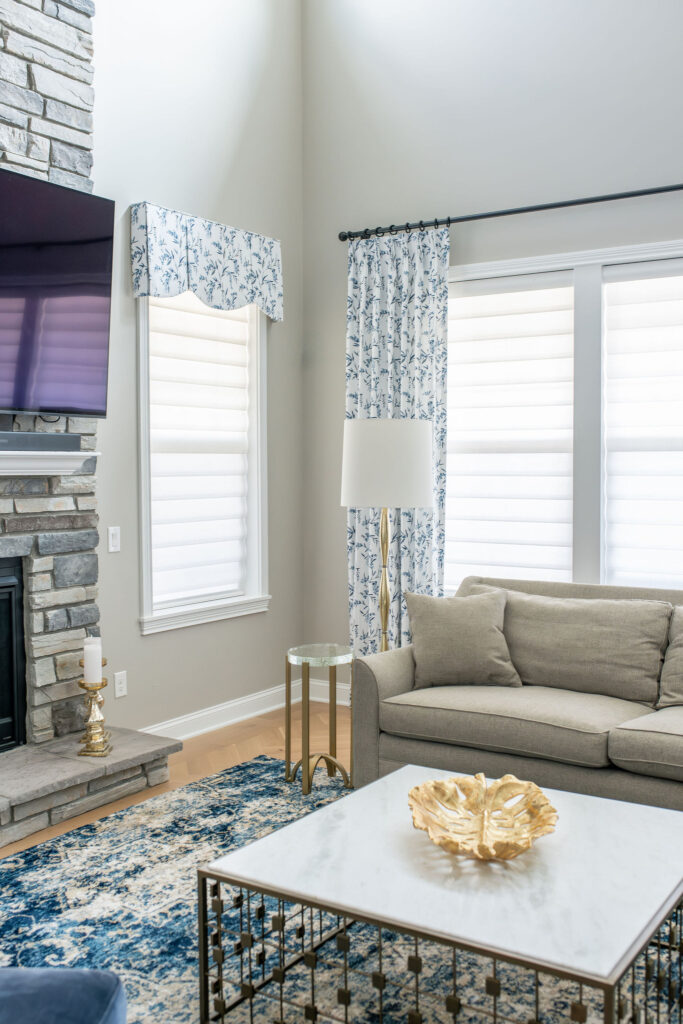 Family room with floral blue custom drapery, cream sofa, and golden accents. Brecksville Ohio interior design Lindsey Putzier 