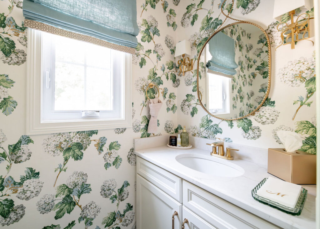 After of the powder room in chagrin falls Ohio with floral wallpaper and gold accents and hardware. Lindsey Putzier interior design 