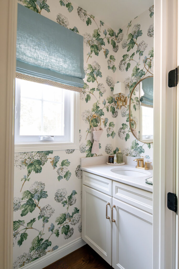 Powder room with floral wallpaper, golden accents, and custom window treatments. Lindsey Putzier interior design Chagrin Falls Ohio