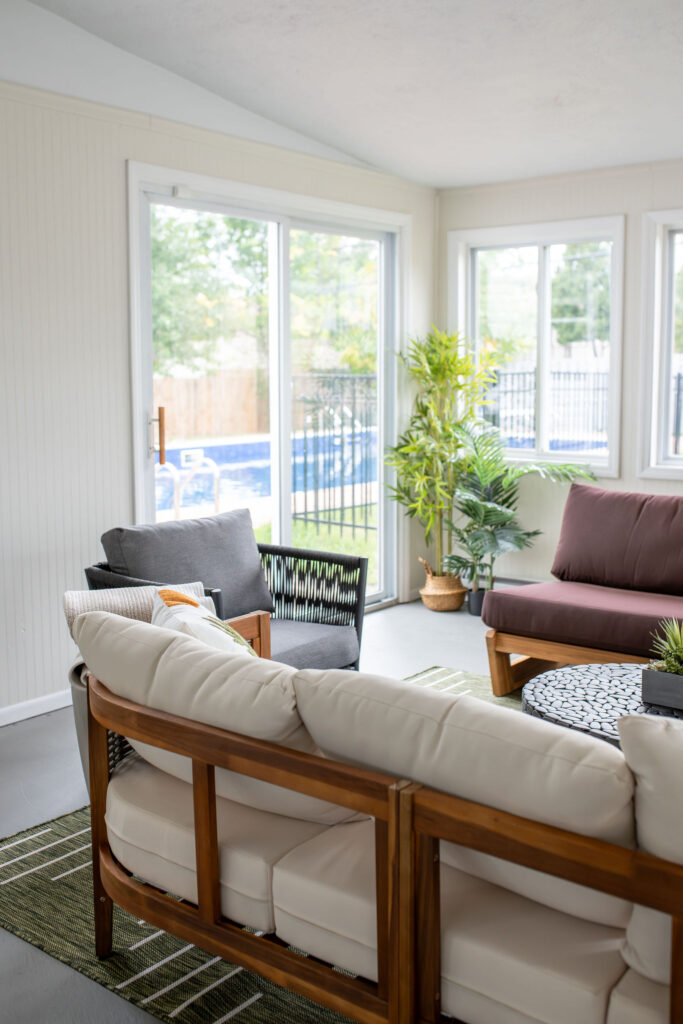 Sun room with wooden bench seating, live plants and earth tone serene accents. Parma Ohio Vacation rentals Lindsey Putzier interior design