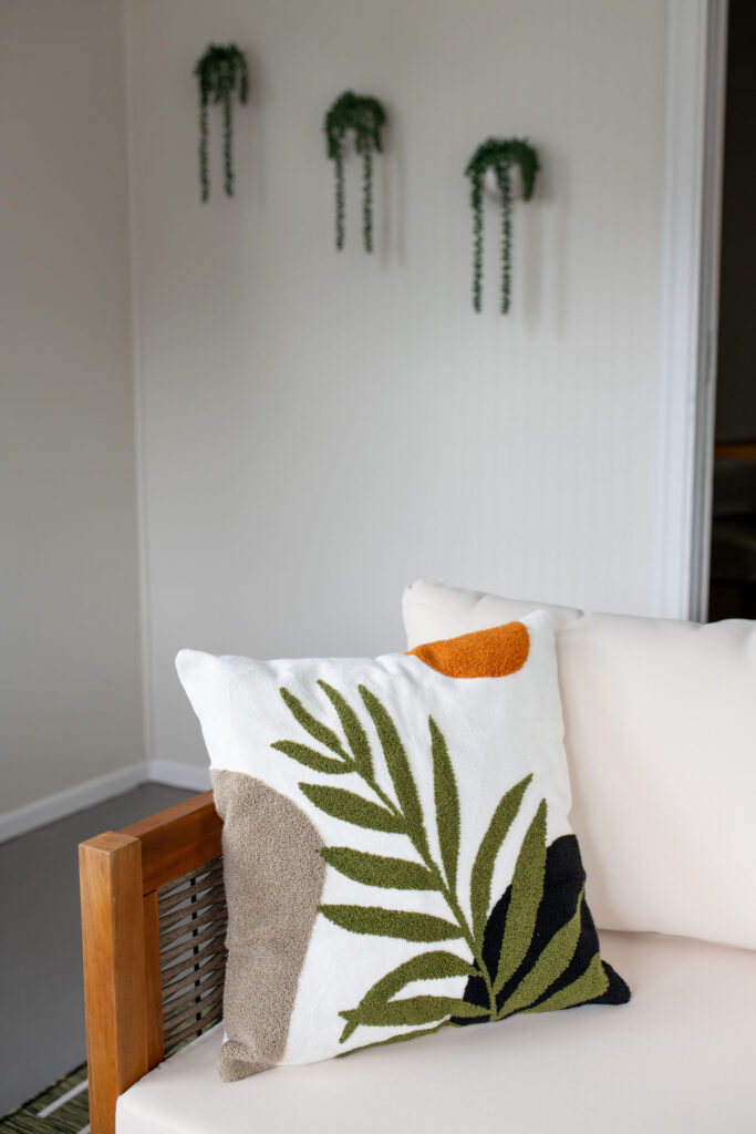 Modern pillow and plants in the sunroom just off the pool. Parma Ohio vacation rental interior design Lindsey Putzier