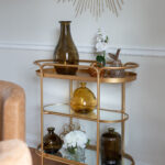 Golden bar cart with brown earthy vases in the dining room of Parma Ohio vacation rental. Lindsey Putzier interior design