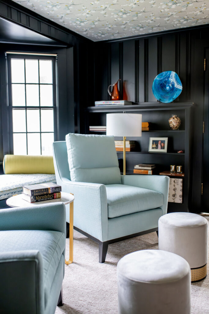 Bright blue upholstered chairs and cream foot stools in the Study with Bookshelves full of treasures. Hudson Ohio interior design Lindsey Putzier