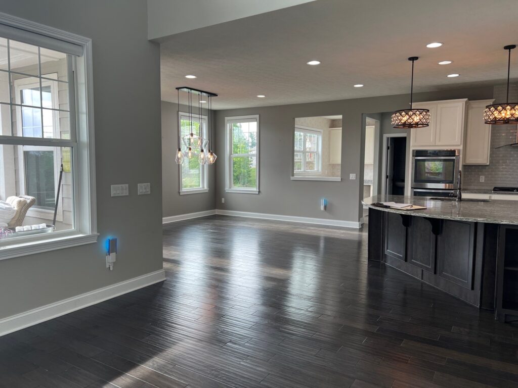 Before of the dining room with dark hardwood flooring, and dated tan walls. Brecksville Ohio interior design Lindsey Putzier 