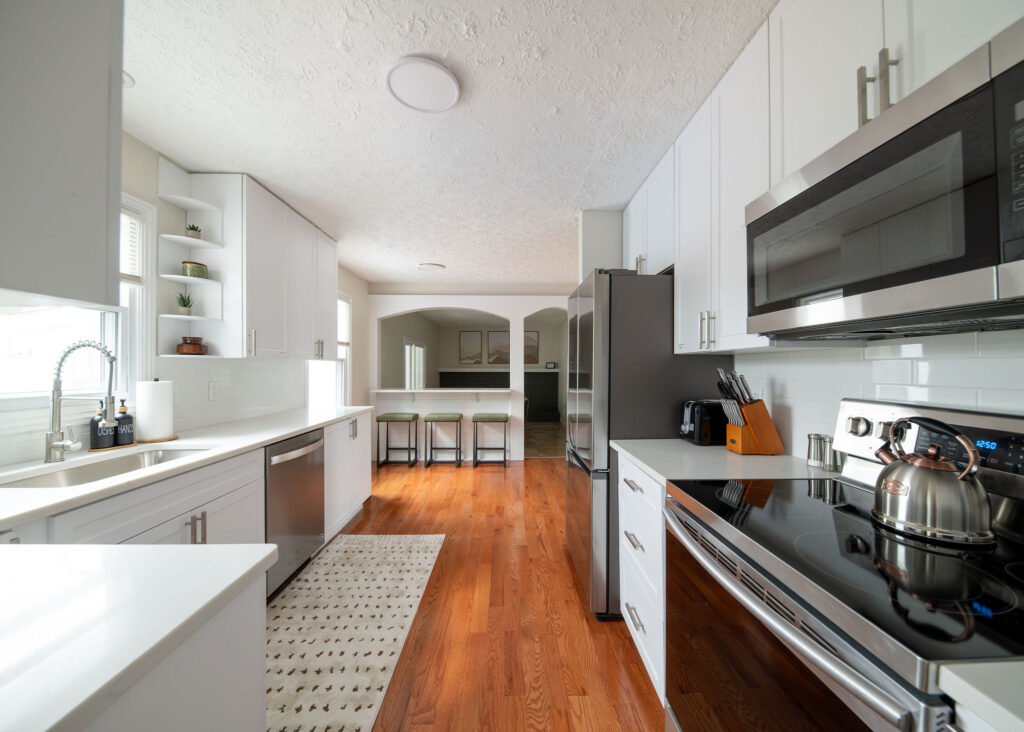 After of the kitchen in Parma Ohio vacation rental with new bar stools and a rug. Lindsey Putzier interior design