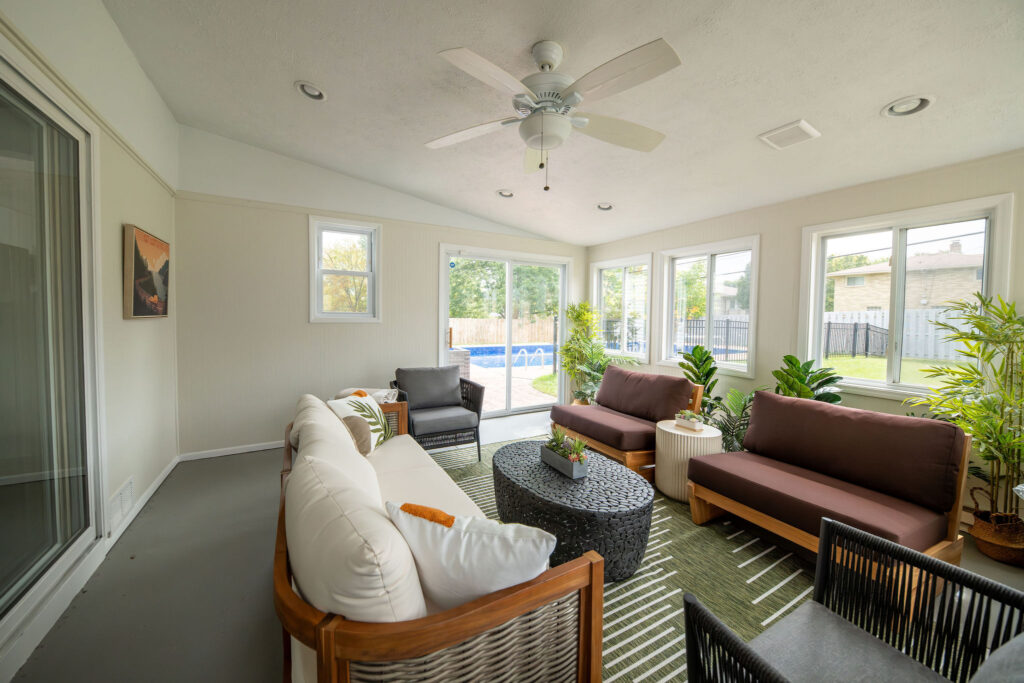 Sun room with tons of seating, outdoor rug and coffee table. Parma Ohio Vacation rental interior design Lindsey Putzier