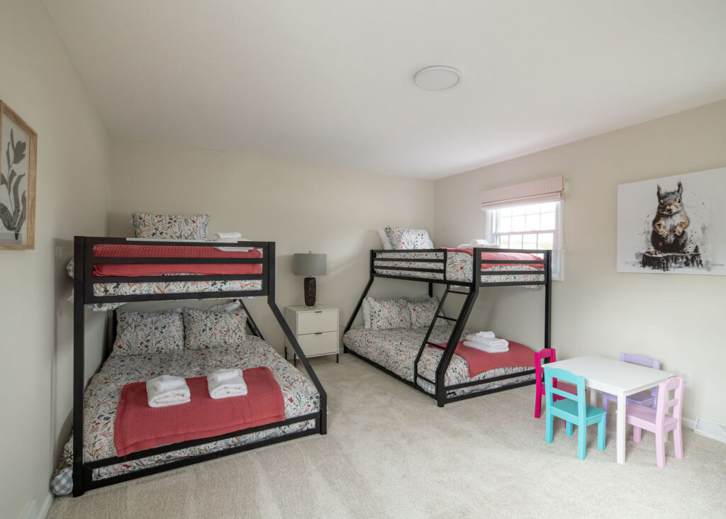 Secondary bedroom with two sets of bunkbeds and children's accessories. Parma Ohio vacation rental interior design Lindsey Putzier