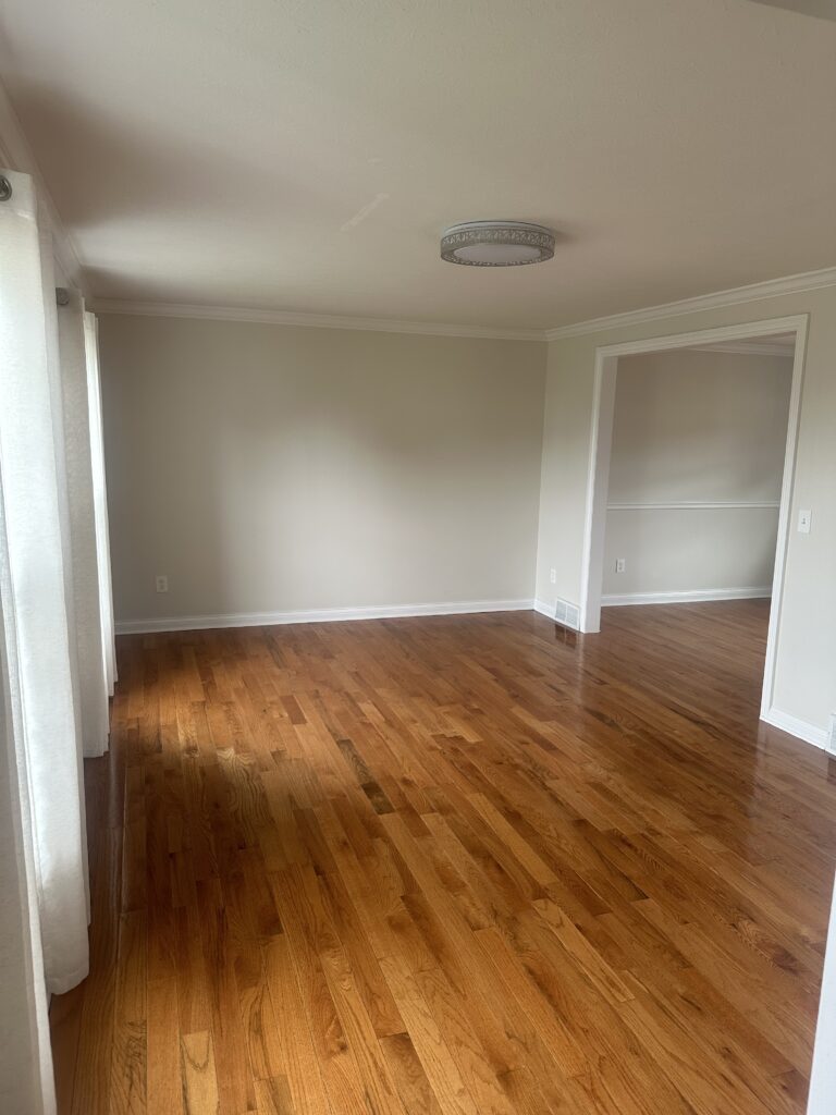Before of living room in Parma Ohio Vacation rental with hardwood floors, cream walls, and white trim. interior design Lindsey Putzier