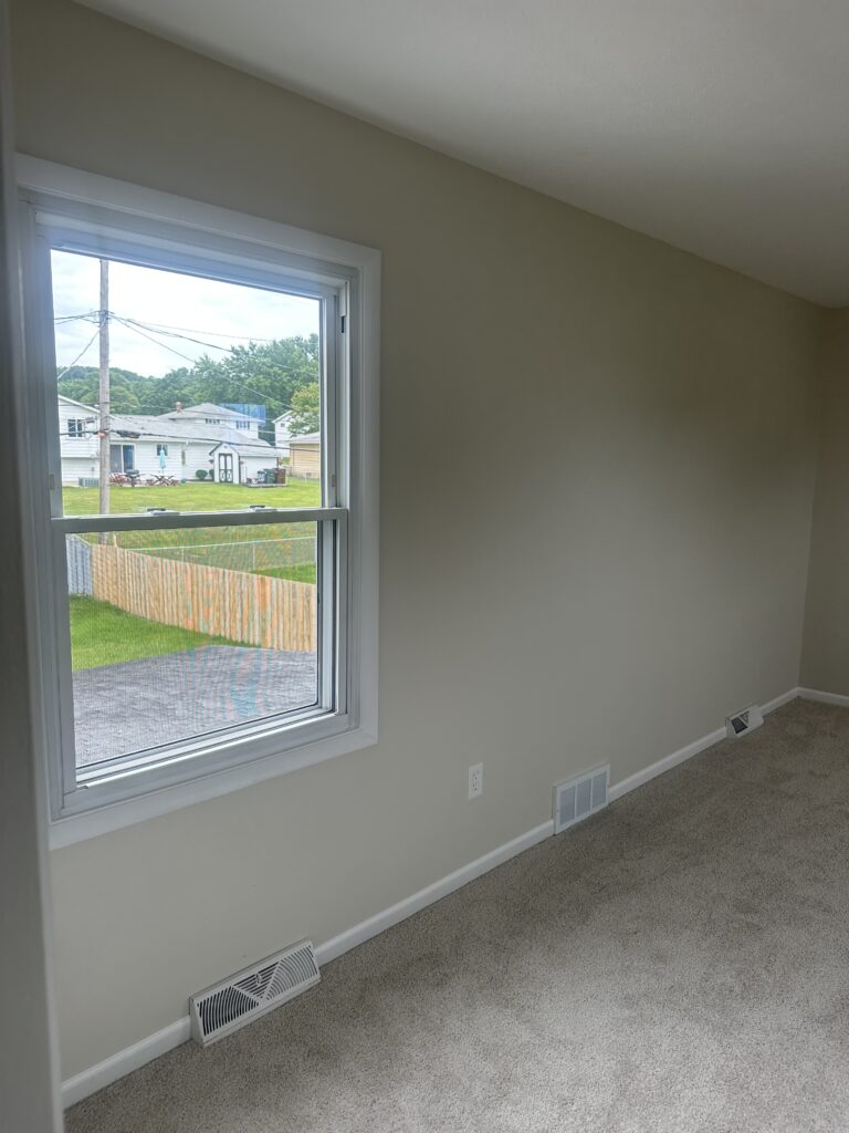 Before of the secondary bedroom with cream walls and carpet. Lindsey Putzier interior design Parma Ohio vacation rental