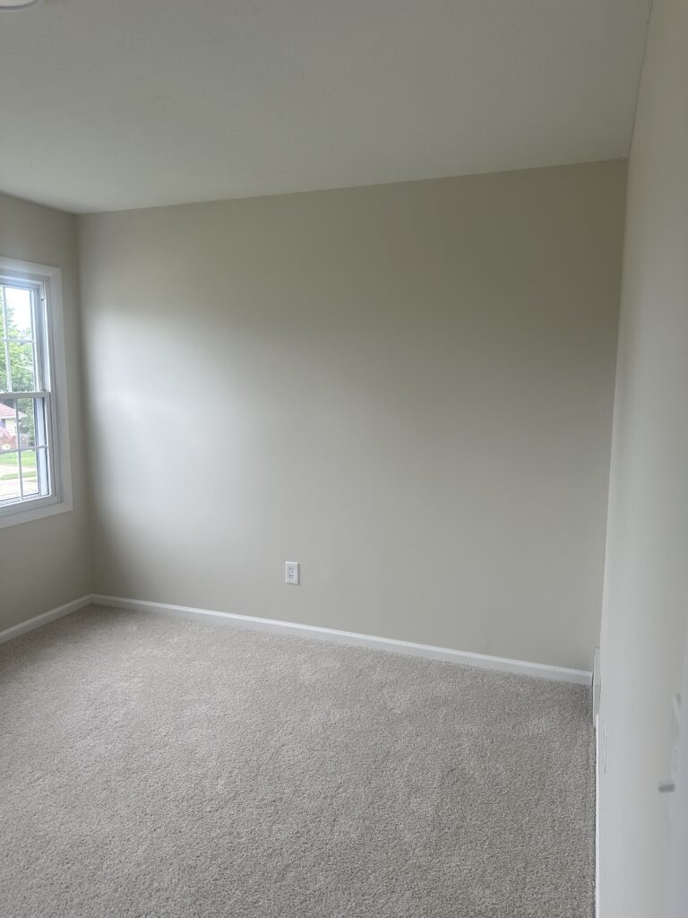 Before of the secondary bedroom with cream walls and carpet. Lindsey Putzier interior design Parma Ohio vacation rental