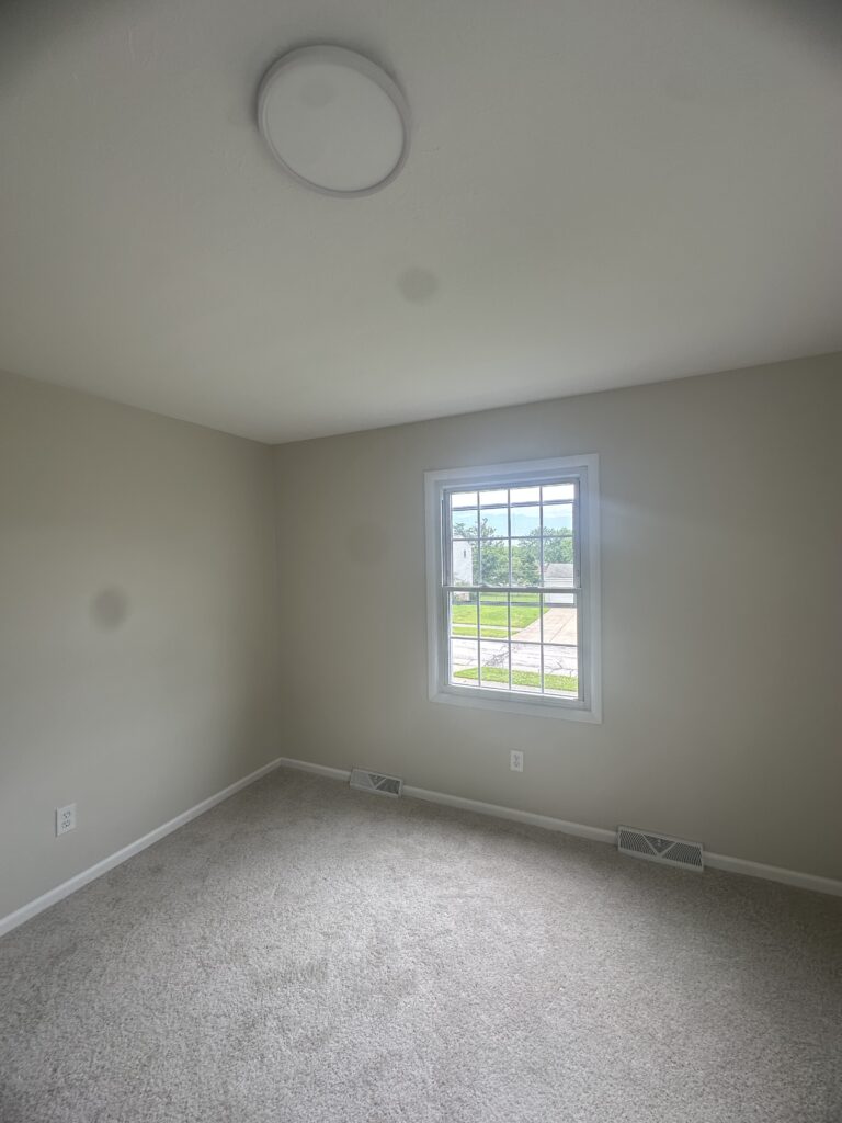 Before of the secondary bedroom with cream walls and carpet. Lindsey Putzier interior design Parma Ohio vacation rental