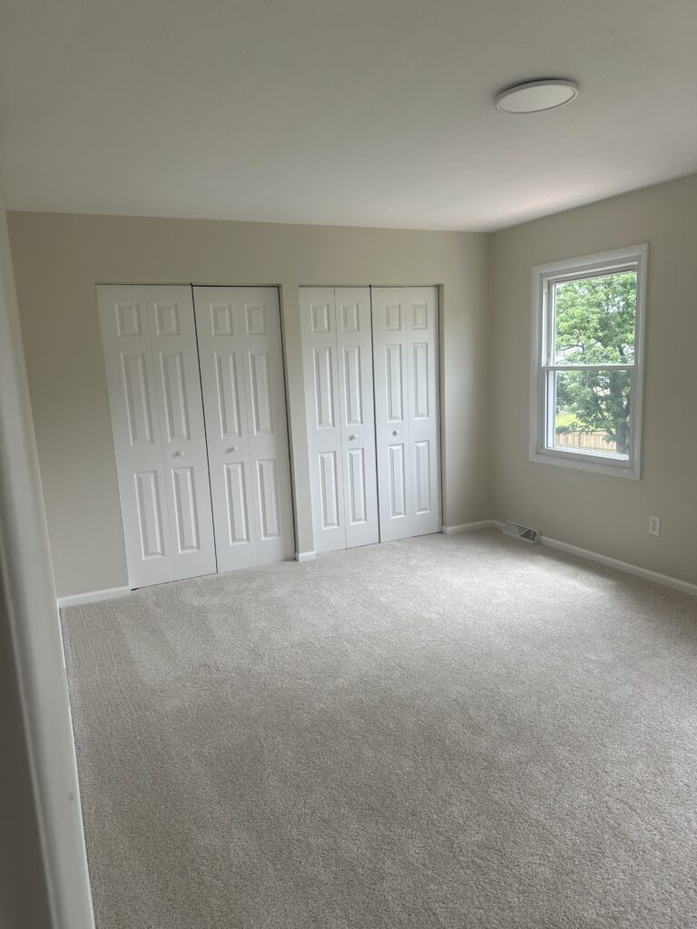 Before of the master bedroom with cream walls and carpet. Lindsey Putzier interior design Parma Ohio vacation rental
