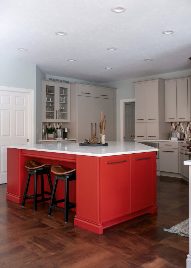 Red updated island in the kitchen with white countertops and wooden barstools. Lindsey Putzier interior design Chagrin Falls