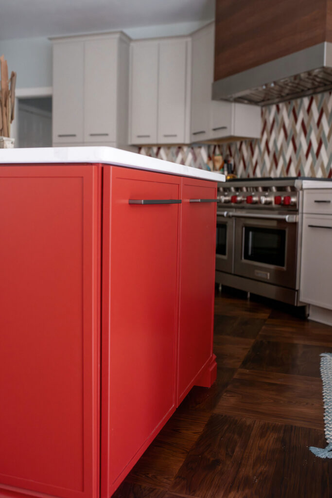 Red island in the kitchen with metal hardware and white stone countertops. Chagrin Falls, Ohio interior design Lindsey Putzier 