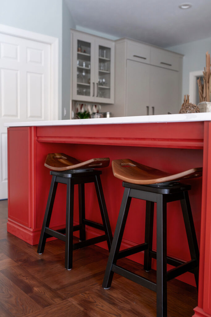Red updated island in the kitchen with white countertops and wooden barstools. Lindsey Putzier interior design Chagrin Falls