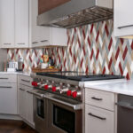 Kitchen remodel in Chagrin Falls with stainless steel appliances, custom dark wooden range, and patterned tiles backsplash. Lindsey Putzier interior design
