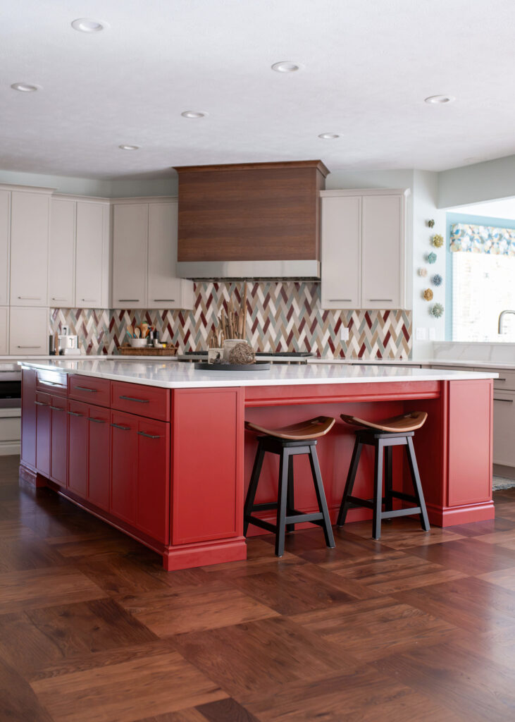 Red updated island in the kitchen with white countertops and wooden barstools. Lindsey Putzier interior design Chagrin Falls