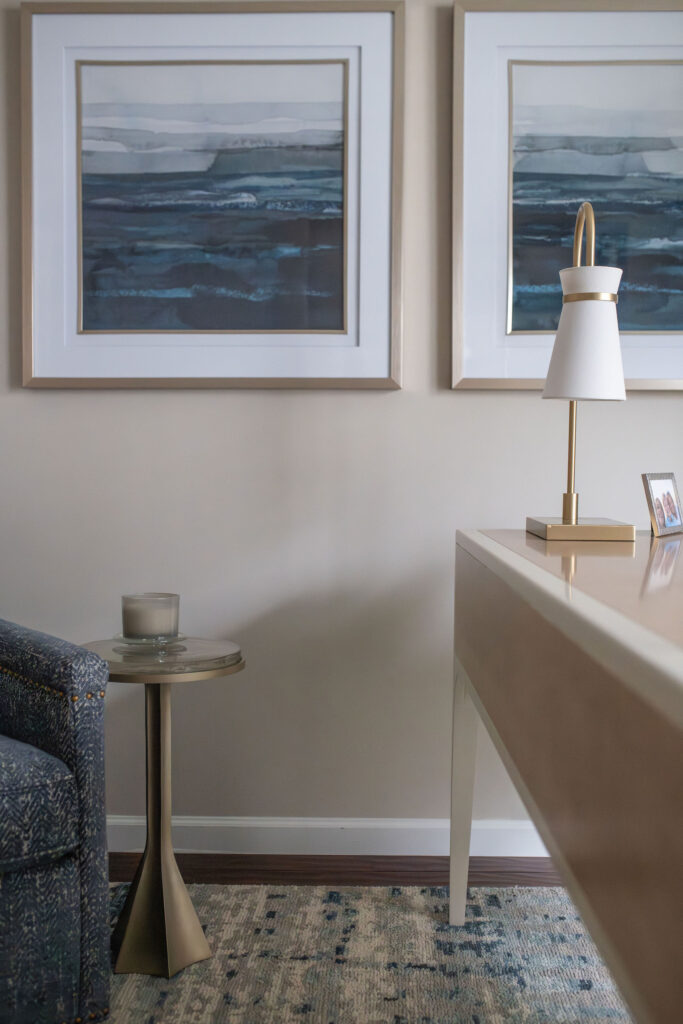 Blue art pieces hanging in the home office with golden accents and wooden desk. Peninsula Ohio interior design Lindsey Putzier